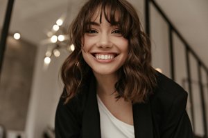 Smiling brunette woman with a wavy wolf cut with voluminous layers